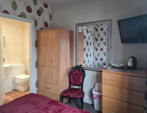 1 dormitorio con cama, espejo y silla en The Buck Inn, en Whitby