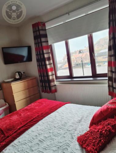 a bedroom with a red bed and a window at The Buck Inn in Whitby