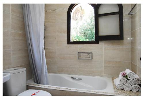 ein Bad mit einer Badewanne, einem WC und einem Fenster in der Unterkunft Apartmentos Nort in Portinatx