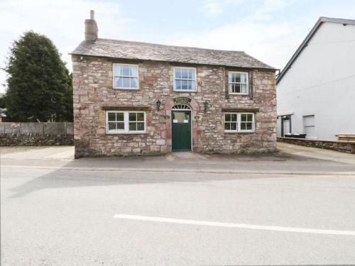 a brick house with a green door on a street at Coach House in Penrith