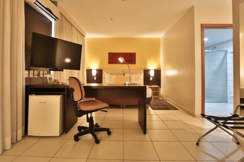 a room with a desk with a computer and a bed at Comfort Hotel Goiânia in Goiânia