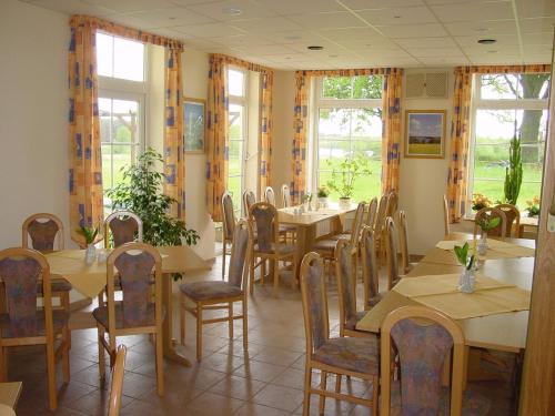 una sala da pranzo con tavoli, sedie e finestre di Landhotel Am Peetscher See a Mirow