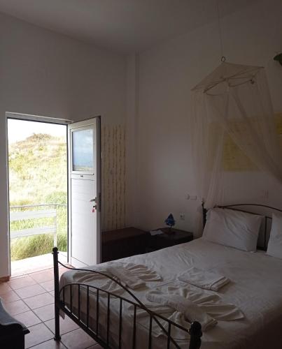 a bedroom with a bed and a large window at PANORAMA in Pitsidia