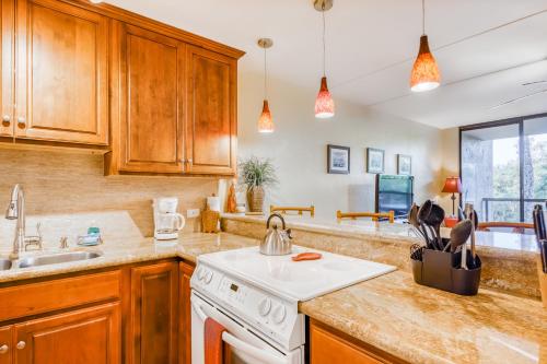a kitchen with wooden cabinets and a white stove top oven at Kona Pacific C421 in Kailua-Kona