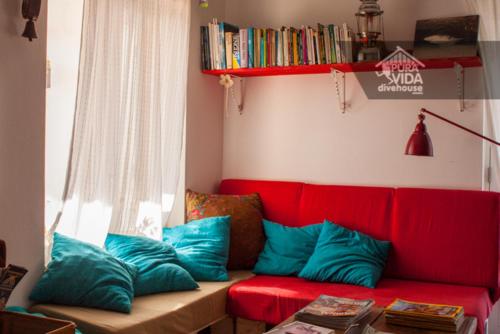 a red couch with blue pillows in a living room at PuraVida Divehouse in Sagres