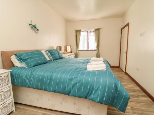 a bedroom with a bed with a blue comforter at Shamrock in Selby