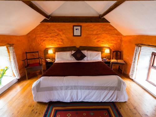 1 dormitorio con 1 cama grande y 2 ventanas en The Stable, en Fethard-on-Sea