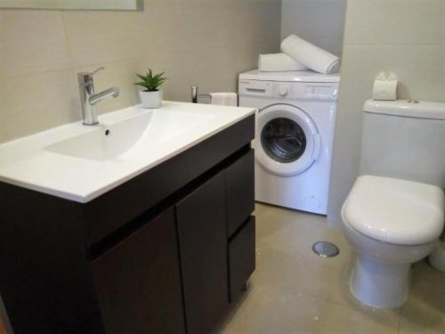 a bathroom with a sink and a washing machine at Dunas 3- Elegante, 150mt Praia, Wifi in Quarteira