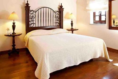 a bedroom with a bed with a white blanket and two lamps at Petritis Guesthouse in Oítilon