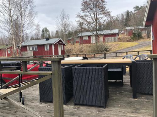 a table and chairs on a deck with a red house at Holiday House with beautiful scenery near Göta Kanal in Undenäs