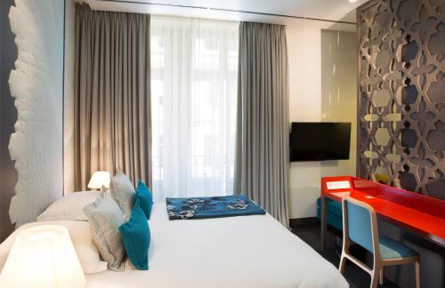 a hotel room with a bed and a desk at Hotel D - Strasbourg in Strasbourg