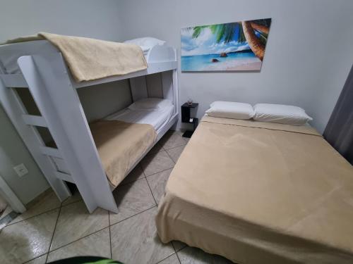 um quarto com 2 beliches e uma fotografia na parede em Flats Aconchego com Ar condicionado em Rio das Ostras