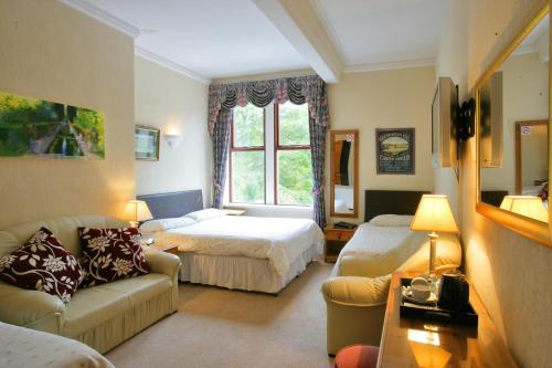 a living room with a couch and a bed and a window at Ilkley Riverside Hotel in Ilkley