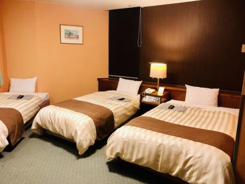 a hotel room with three beds and a lamp at Fuji Green Hotel - Vacation STAY 18923v in Fuji
