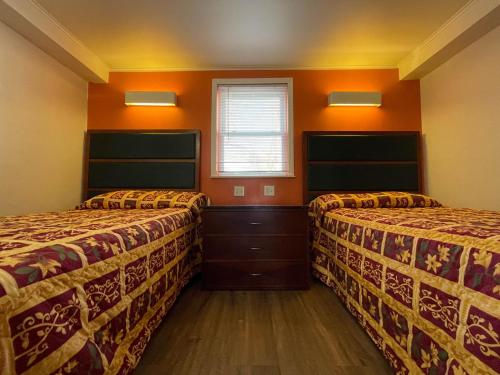 2 łóżka w pokoju z pomarańczowymi ścianami w obiekcie Tinton Falls NJ Neptune w mieście Tinton Falls