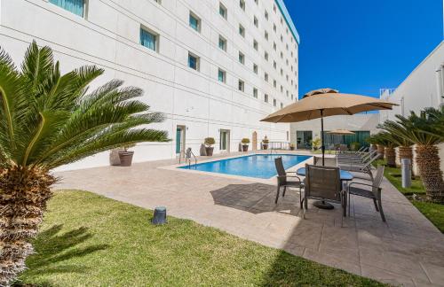 a patio with a table and chairs and an umbrella at Hotel Aeropuerto Los Cabos in San José del Cabo