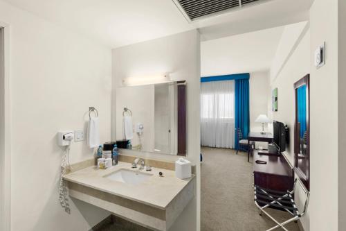 a bathroom with a sink and a large mirror at Hotel Aeropuerto Los Cabos in San José del Cabo