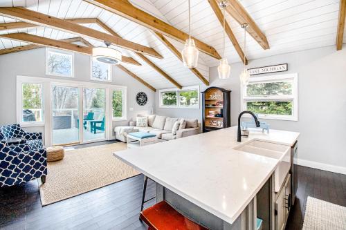 a kitchen and living room with white walls and wooden ceilings at The Gatehouse on Orchard Beach in Lakeside