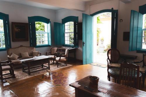 a living room with a couch and chairs and windows at Pousada Richard Rothe in Tiradentes