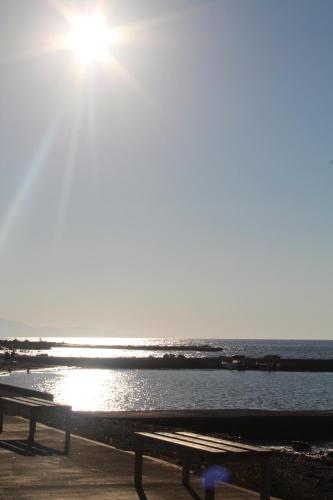 a bench sitting next to a body of water at Blue Sand Apartment in Analipsi