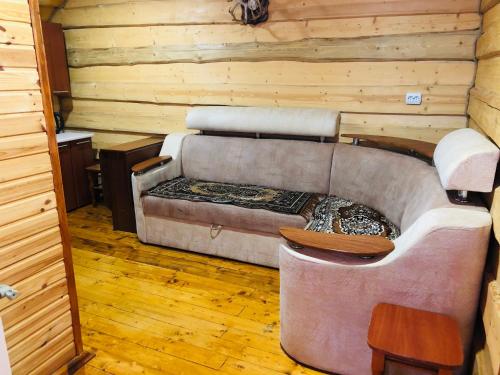 una sala de estar con sofá en una cabaña de madera en У Віти номер3, en Synevyrsʼka Polyana