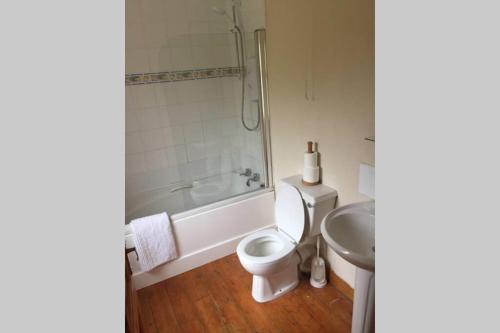 y baño con aseo, bañera y lavamanos. en Heron Water Cottage, en Killarney
