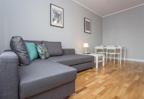 a living room with a gray couch and a table at CR Apartament Centrum Zamenhofa 1 in Białystok