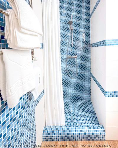 a bathroom with a shower with a blue tiled floor at Lucky Ship Art Hotel in Odesa