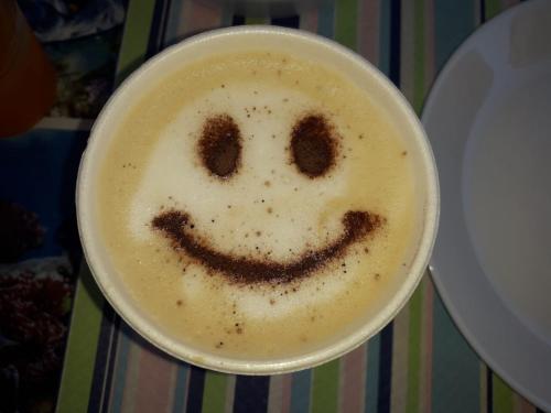 una tazza di cappuccino con una faccina sorridente in cima di Affittacamere Villa Zelinda a Sirolo