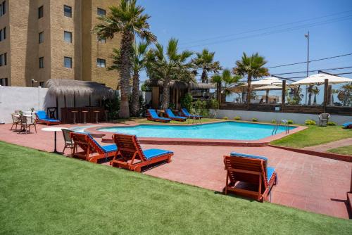una piscina con tumbonas, una mesa y una piscina en Hotel Canto del Mar, en La Serena