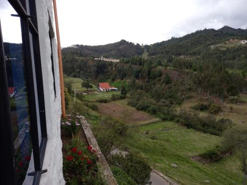 a view from a window of a field and a house at Restaurante y Hostal: De La Villa Pa Sumercé in Monguí