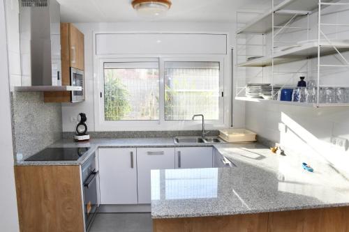 una cocina con armarios blancos y una ventana en Casa Teresita, en Deltebre