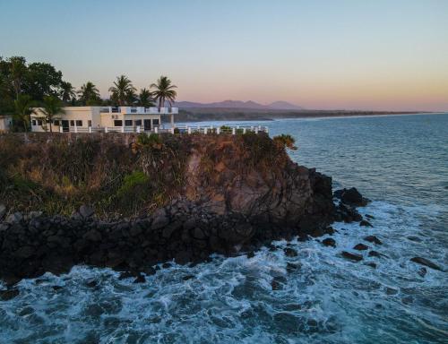 a house on a rocky island in the ocean at Paradise Surf Hotel in San Miguel