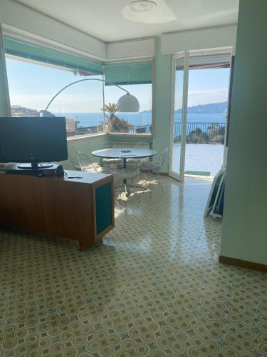 a living room with a tv and a table and glass doors at Grande Attico con Vista Vicino al Centro by PortofinoVacanze in Rapallo