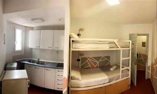 リョレート・デ・マルにあるApartments centro Lloret para 6の二段ベッド1組、キッチンが備わる小さな客室です。