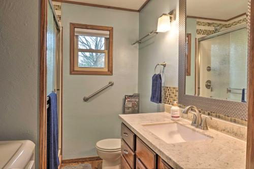 ein Badezimmer mit einem Waschbecken, einem WC und einem Spiegel in der Unterkunft Table Rock Lake House with Fire Pit Steps to Water! in Branson West