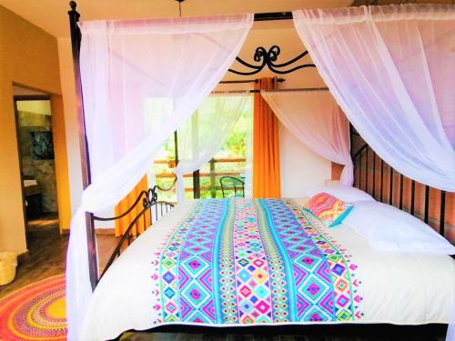 a bedroom with a canopy bed with white curtains at Hotel Boutique Jardín de Flores in Tlayacapan