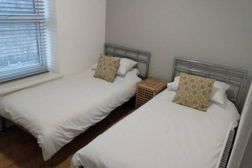 2 camas individuales en una habitación con ventana en 3 Story House near Bike park Wales & zip world, en Aberaman