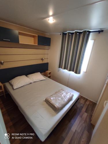 Cette petite chambre dispose d'un grand lit et d'une fenêtre. dans l'établissement Mobil home 5-6 personnes - climatisé, à Port-la-Nouvelle