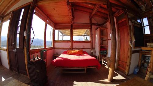 um quarto com uma cama vermelha num quarto com janelas em Cabaña La Linda - Complejo El Taller em Potrerillos
