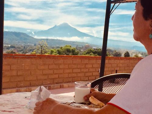 een vrouw aan een tafel met een glas melk bij Hotel Boutique Jardín de Flores in Tlayacapan