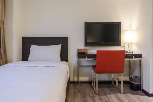 a bedroom with a bed and a desk with a television at Jih Lih Hotel in Magong