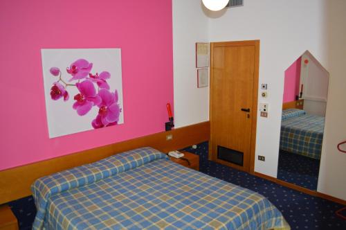 a hotel room with two beds and a pink wall at Hotel Azzurra in Sirmione
