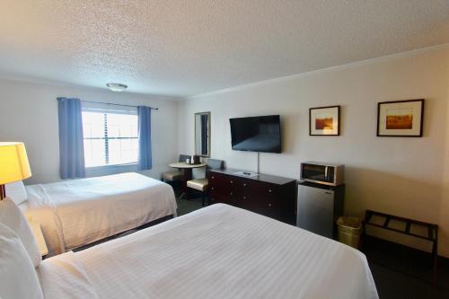 a hotel room with two beds and a flat screen tv at At Home Inn - Pensacola in Pensacola