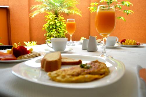 a table with a plate of food and glasses of orange juice at Hotel Mare Apartasuite in Cali