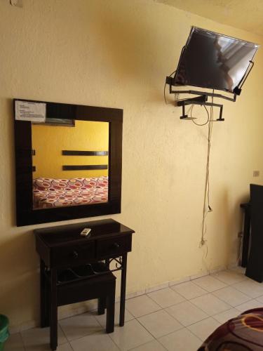 a mirror on a wall with a table and a tv at Hotel Posada del Ángel in Villahermosa