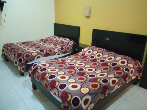 two beds in a hotel room with colorful covers at Hotel Posada del Ángel in Villahermosa