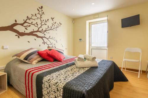 a bedroom with a bed with a tree mural on the wall at Casa do Alto do Vez in Balouta
