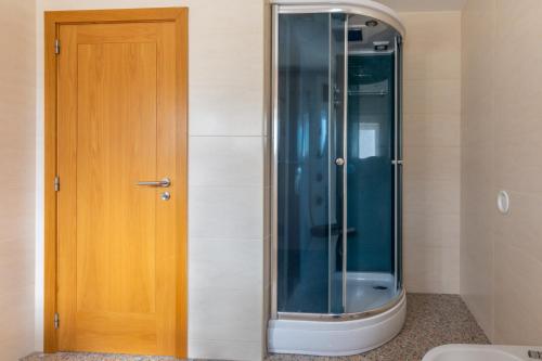 a shower in a bathroom with a wooden door at Casa do Alto do Vez in Balouta