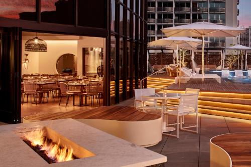 a restaurant with tables and chairs and a fire pit at Hyatt Centric Waikiki Beach in Honolulu